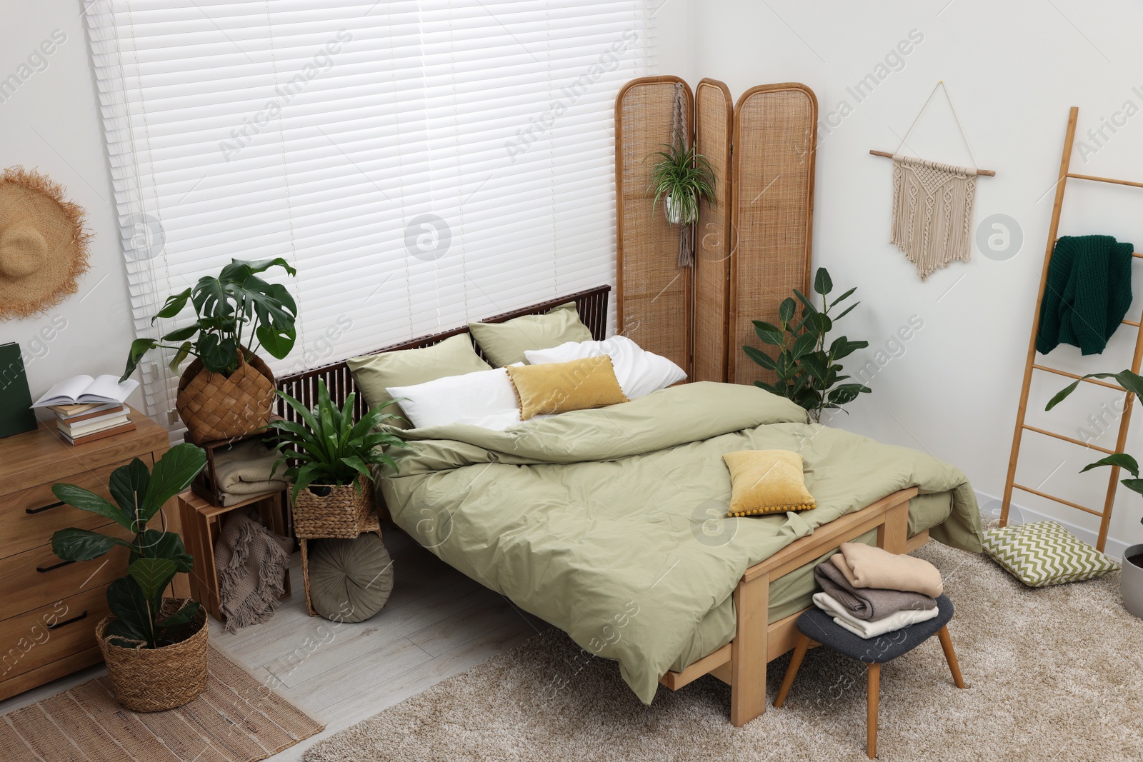 Photo of Stylish bedroom with comfortable bed and beautiful green houseplants, above view. Interior design