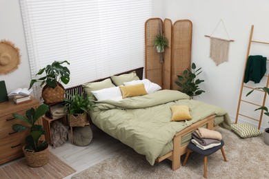 Photo of Stylish bedroom with comfortable bed and beautiful green houseplants, above view. Interior design