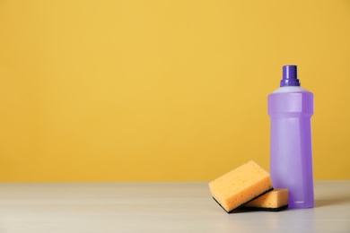 Photo of Bottle of cleaning product and sponges on light table. Space for text