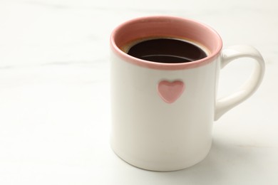 Cup of aromatic coffee on white table, closeup. Space for text