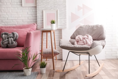 Photo of Stylish living room interior with sofa and rocking armchair near brick wall