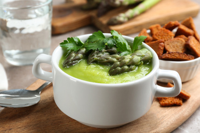 Delicious asparagus soup served on table, closeup