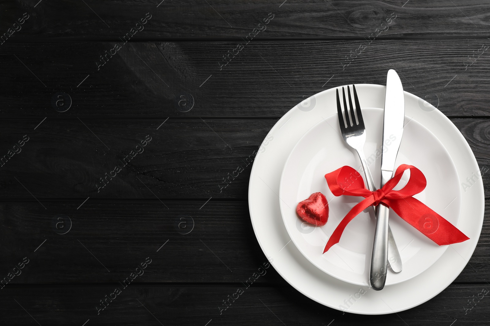 Photo of Beautiful table setting on black wooden background, top view with space for text. Valentine's Day dinner