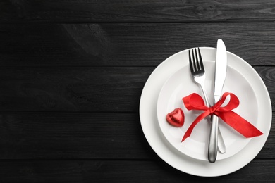 Photo of Beautiful table setting on black wooden background, top view with space for text. Valentine's Day dinner