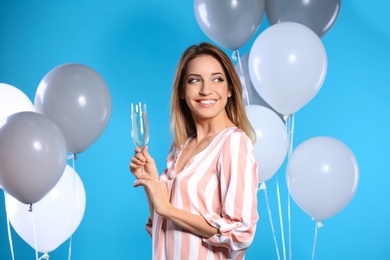 Photo of Portrait of happy woman with champagne in glass and party balloons on color background