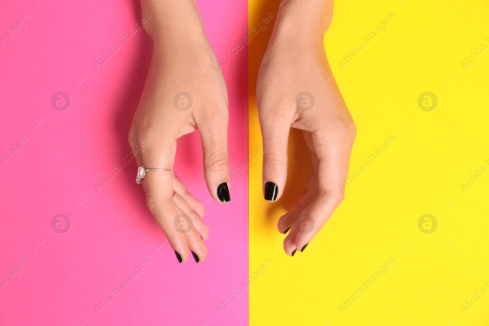 Photo of Woman showing manicure with black nail polish on color background, top view
