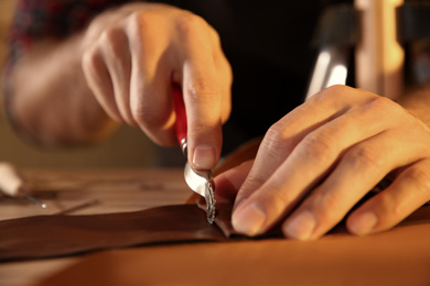 Man marking leather with roller in workshop, closeup