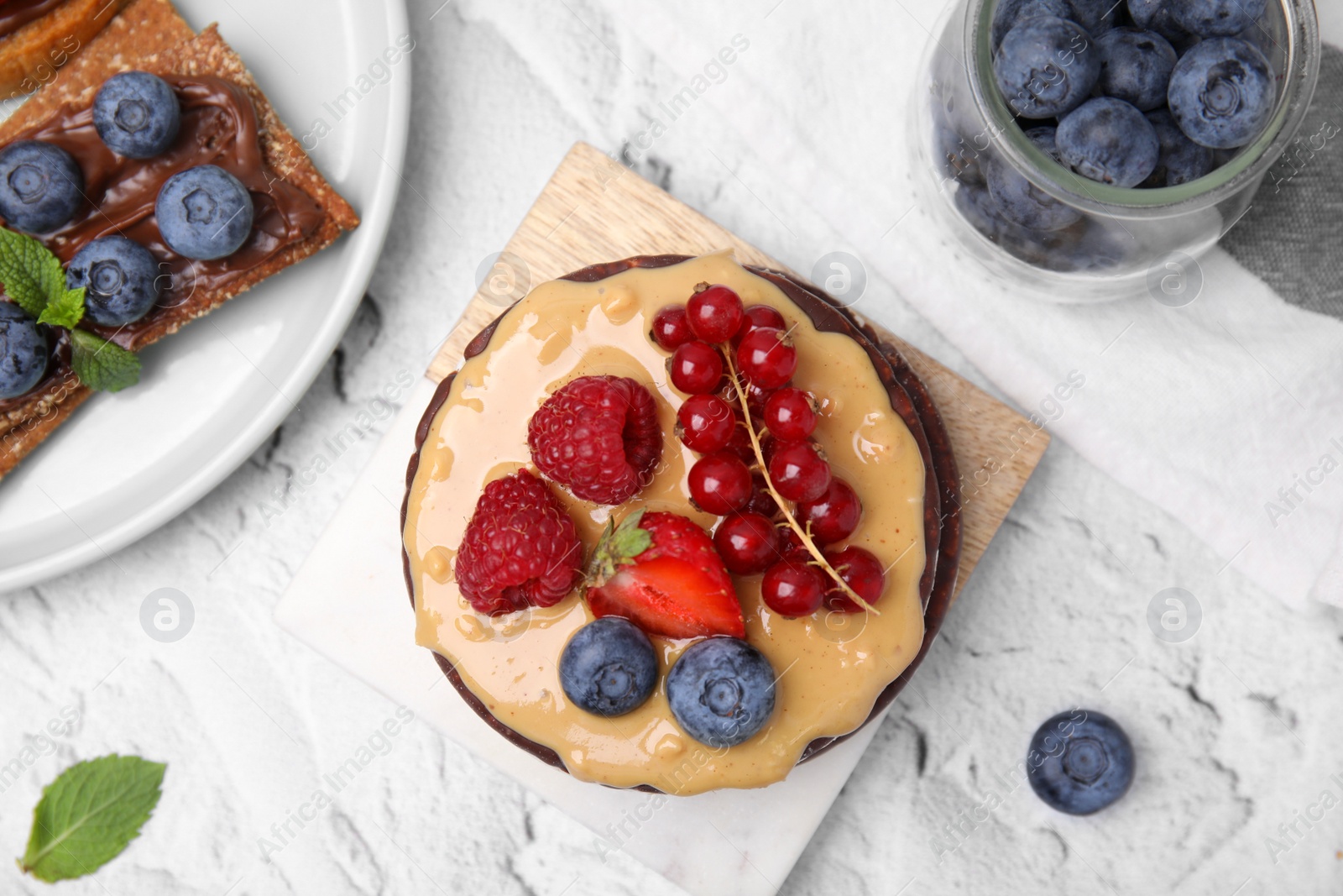 Photo of Crunchy rice cakes and rye crispbreads with different toppings on white textured table, flat lay