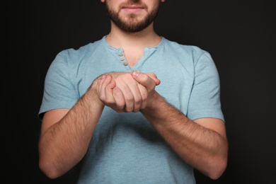 Photo of Man showing BELIEVE gesture in sign language on black background, closeup