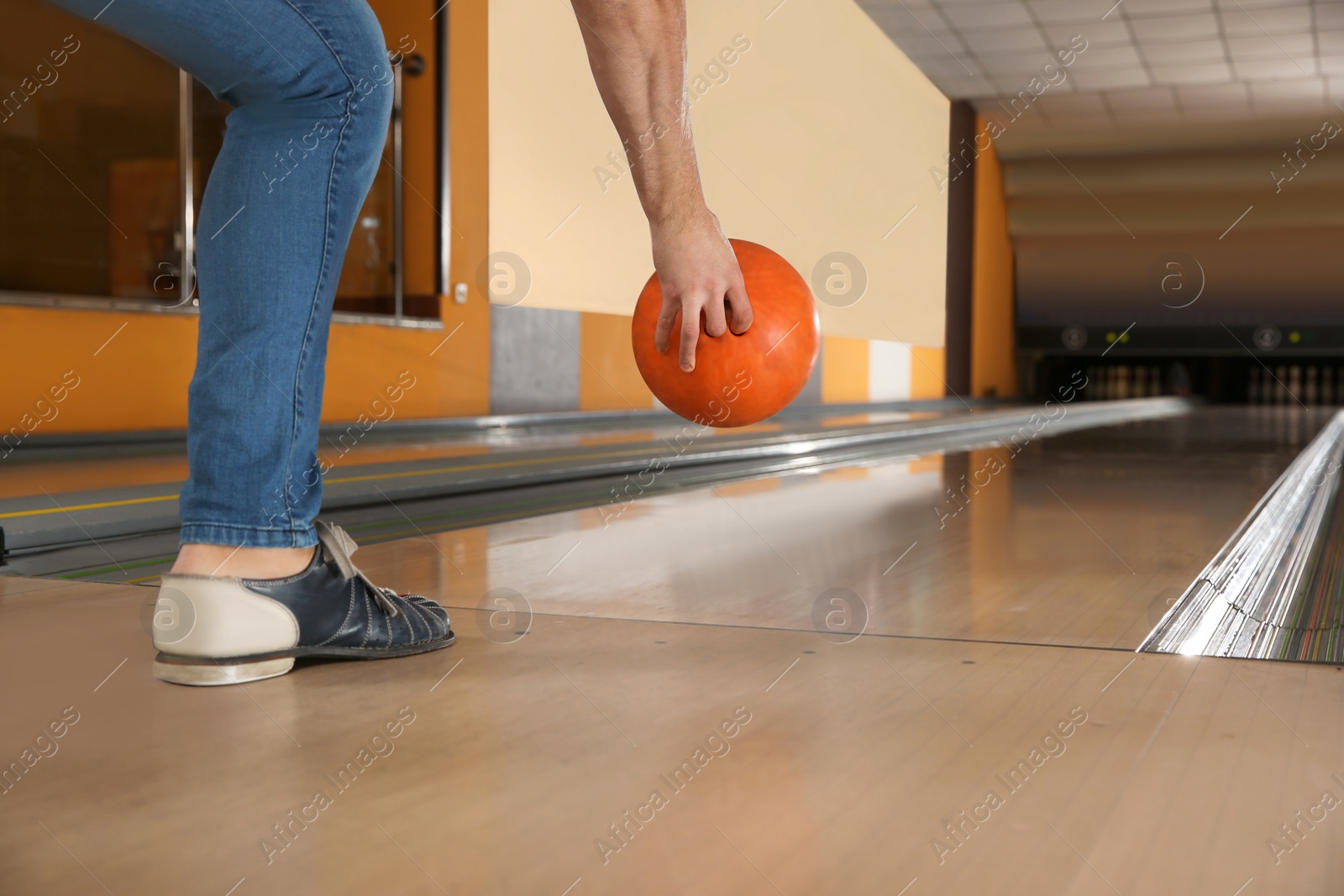 Photo of Young man throwing ball in bowling club, closeup