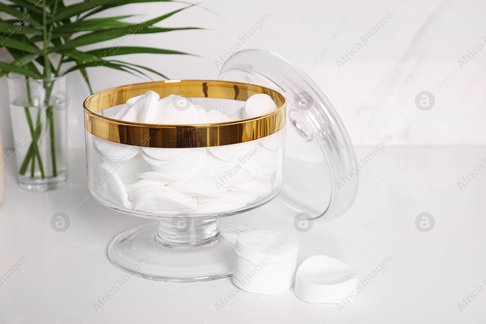 Photo of Glass jar with cotton pads on table in bathroom