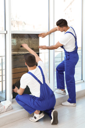 Professional workers tinting window with foil indoors