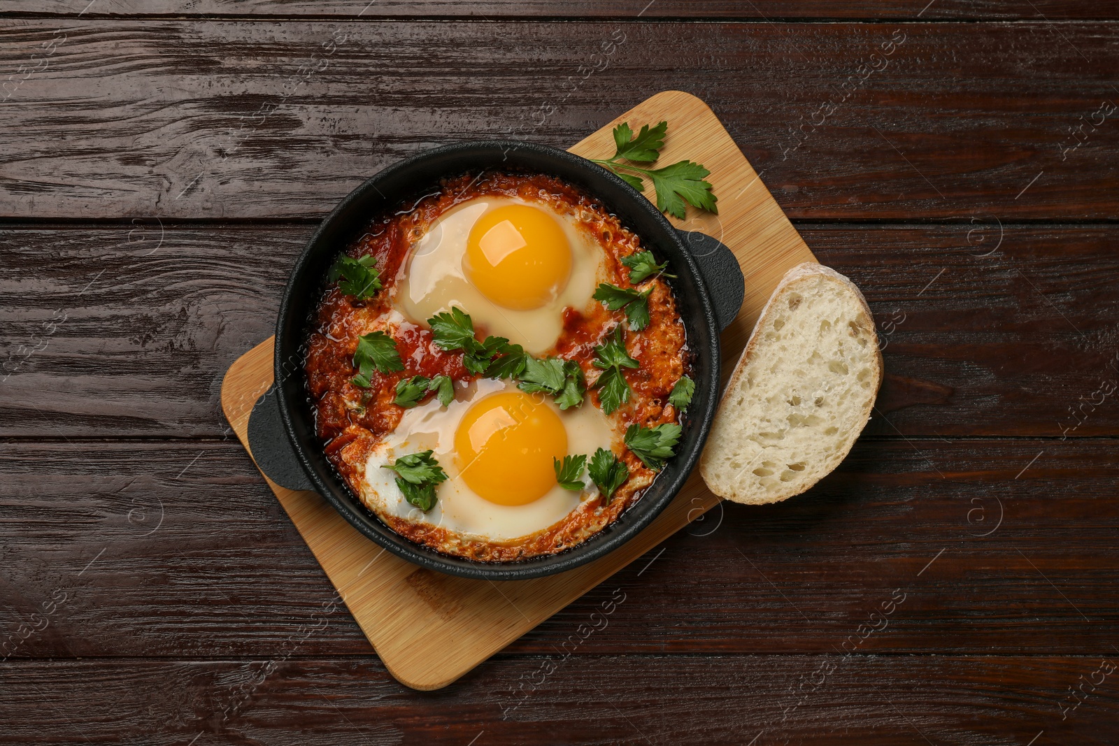 Photo of Delicious shakshuka in frying pan on wooden table, top view