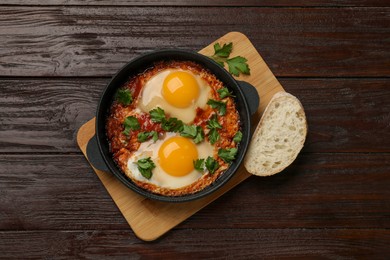 Photo of Delicious shakshuka in frying pan on wooden table, top view