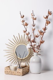 Home decor and vase with cotton branches on table against white background