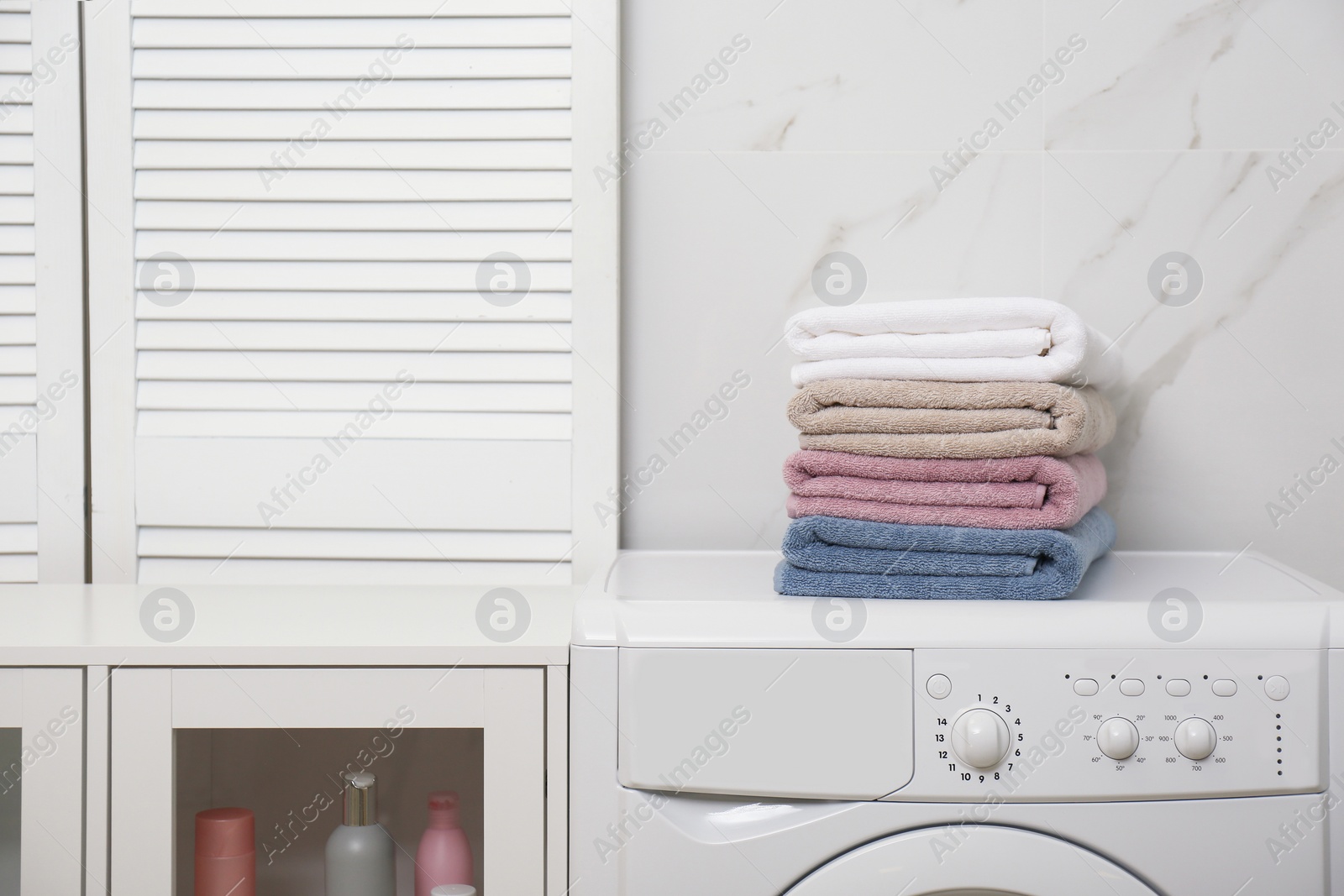 Photo of Stack of fresh towels on washing machine in laundry room