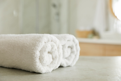 Photo of Clean rolled towels on table in bathroom