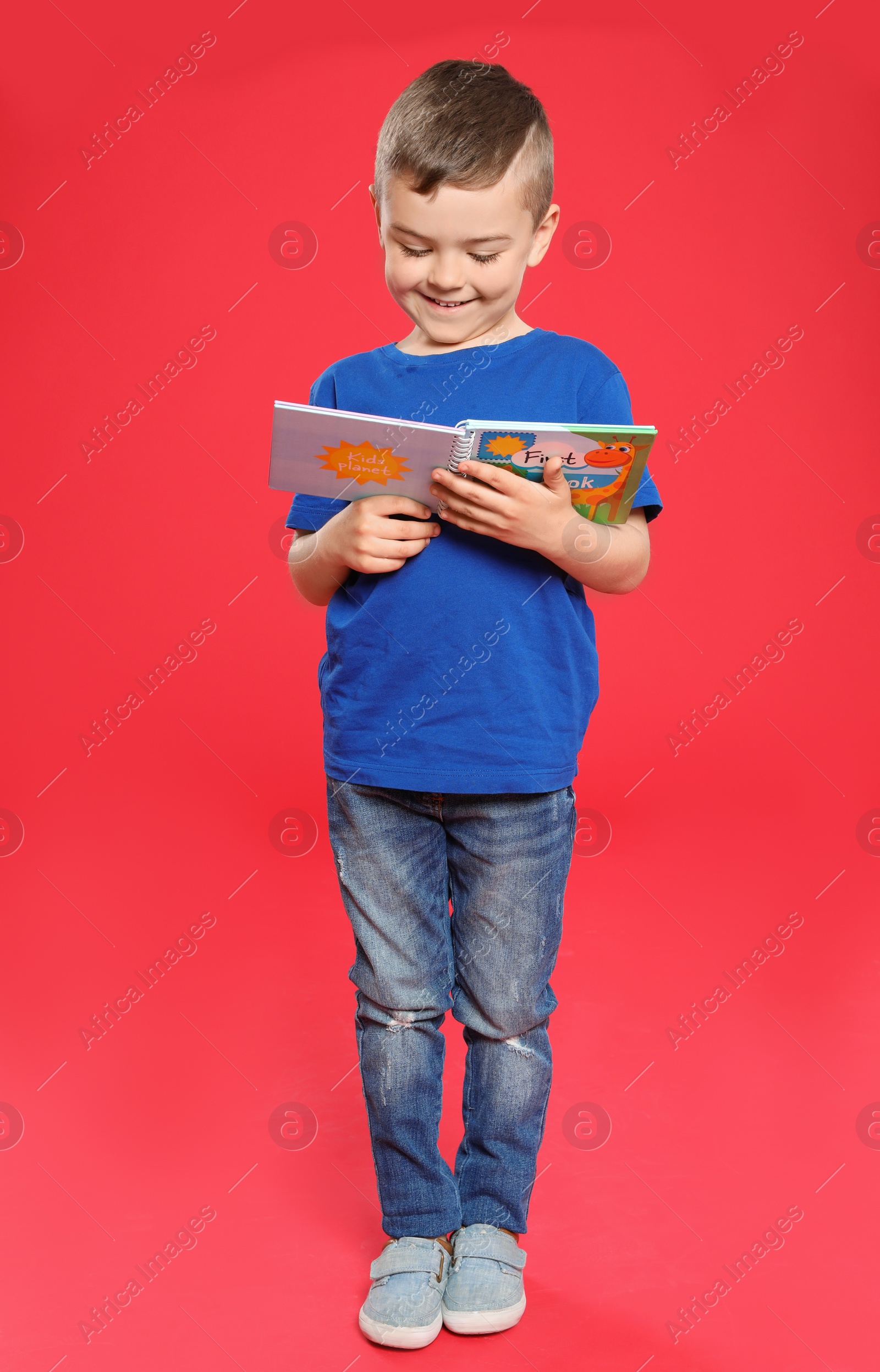 Photo of Cute little boy reading book on color background