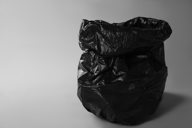 Photo of Trash bag full of garbage on grey background. Space for text