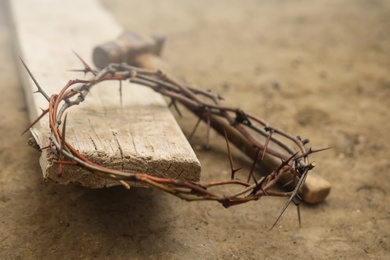 Photo of Crown of thorns, hammer and wooden plank on ground. Easter attributes