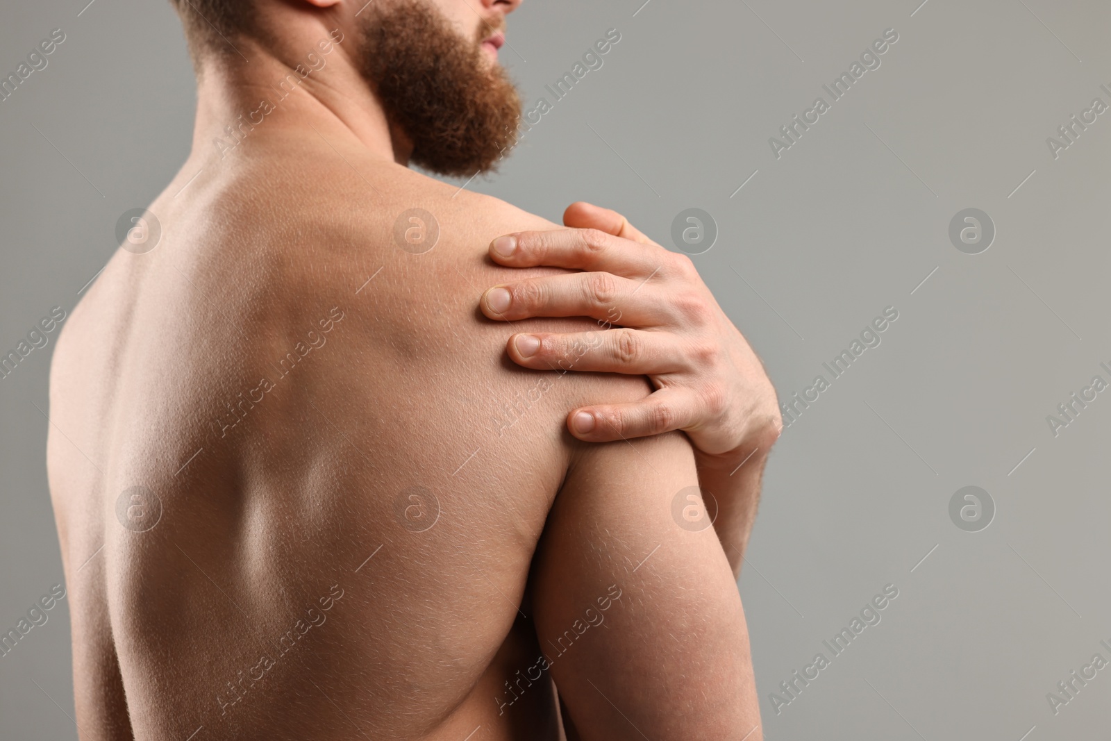 Photo of Man touching his shoulder on light grey background, closeup