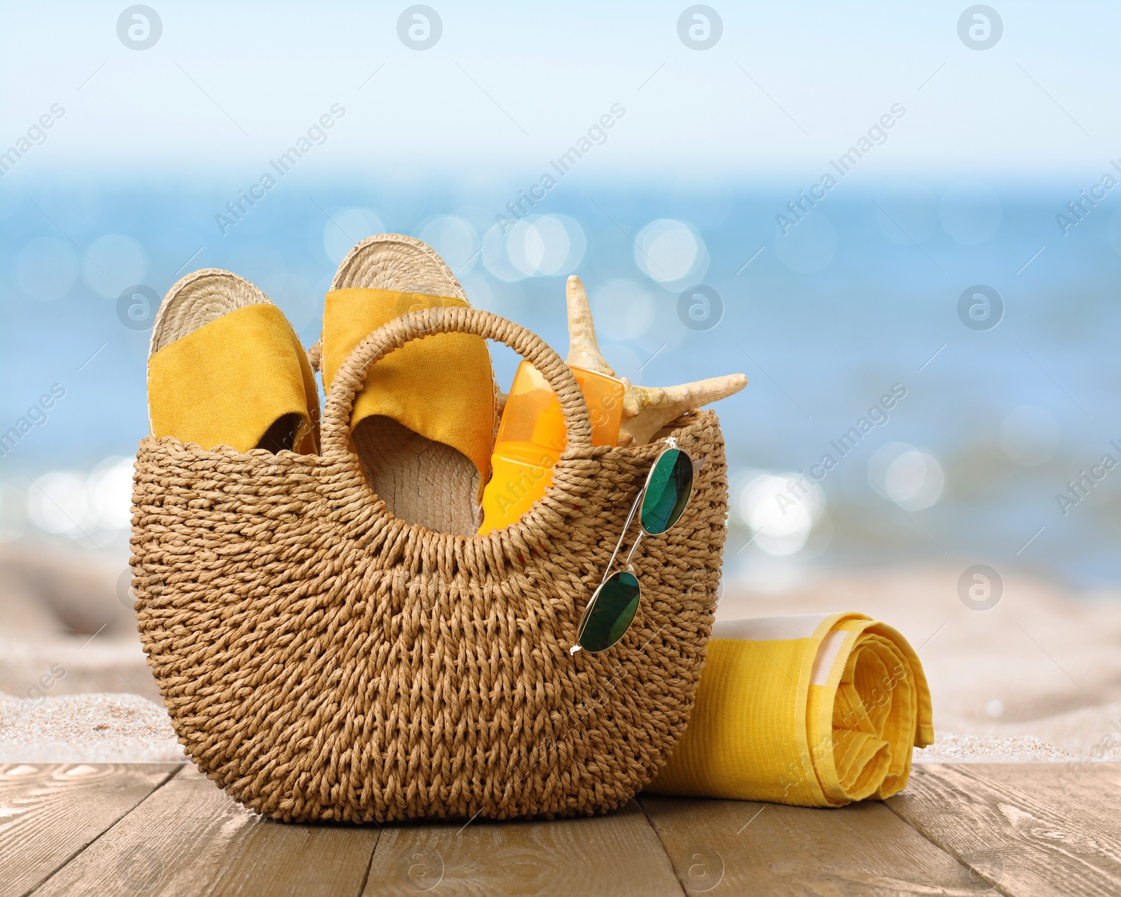 Image of Bag with sunscreen and accessories on sunny ocean beach. Summer vacation