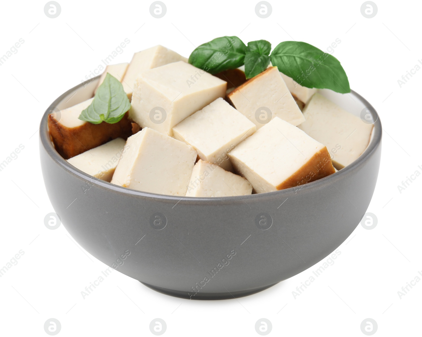 Photo of Bowl of delicious smoked tofu cubes with basil isolated on white