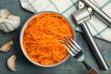 Photo of Delicious Korean carrot salad and garlic on blue wooden table, flat lay