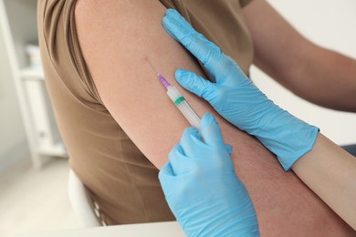 Doctor giving hepatitis vaccine to patient in clinic, closeup
