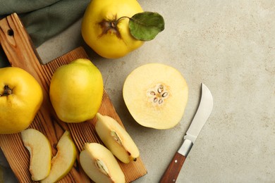 Photo of Tasty ripe quince fruits and knife on grey table, flat lay. Space for text