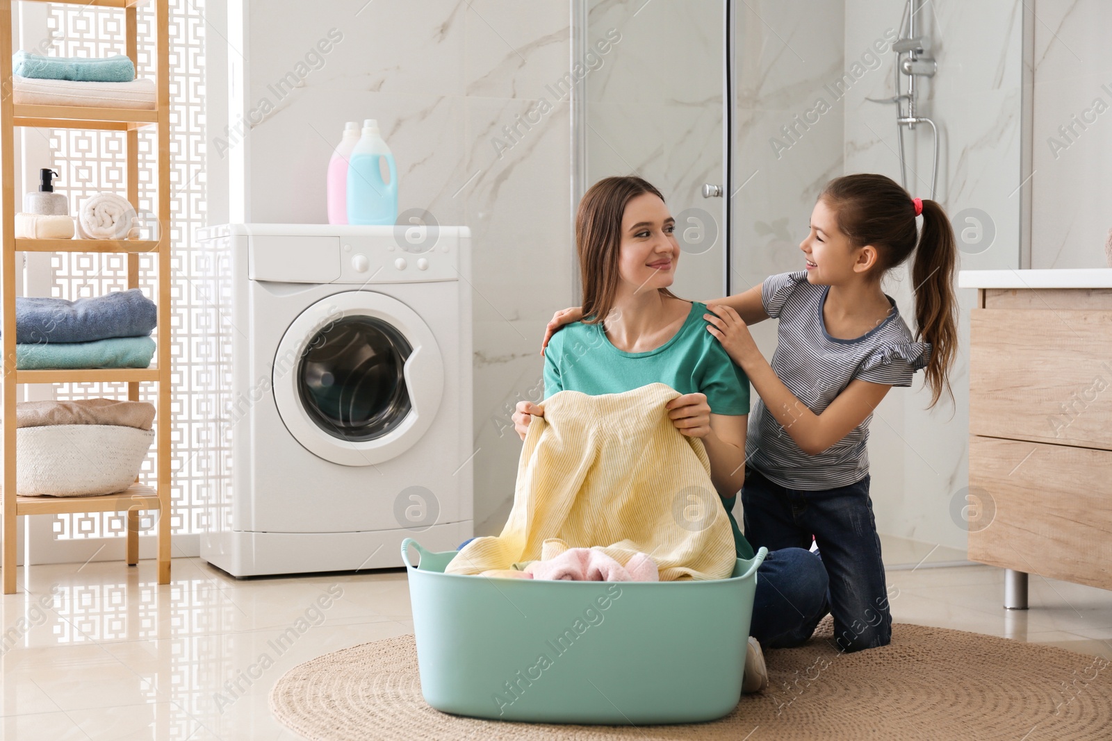 Photo of Mother and little daughter with clean laundry in bathroom