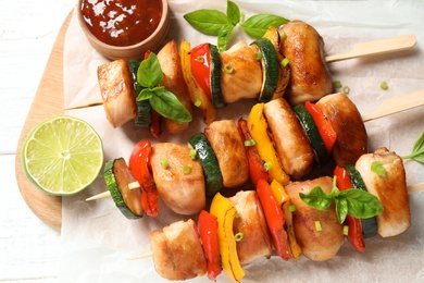 Photo of Delicious chicken shish kebabs with vegetables and lime on white wooden table, top view