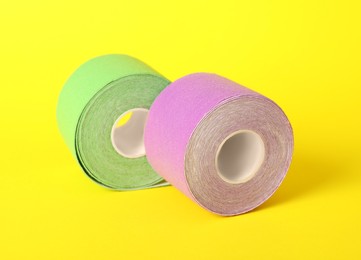 Photo of Bright kinesio tape in rolls on yellow background