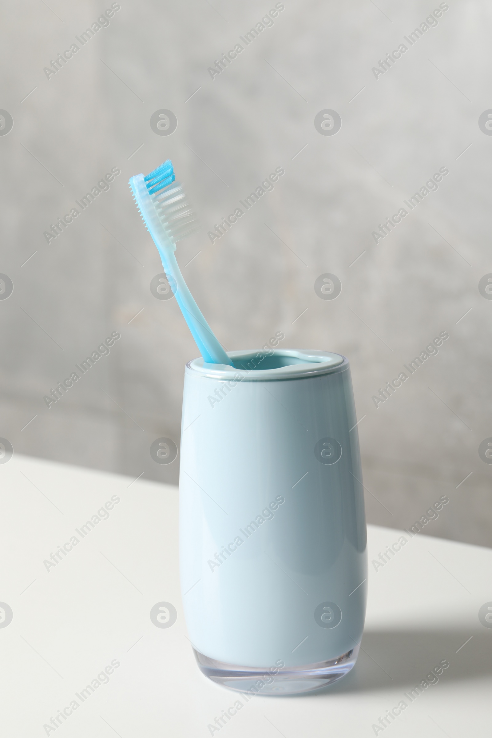 Photo of Plastic toothbrush in holder on white countertop
