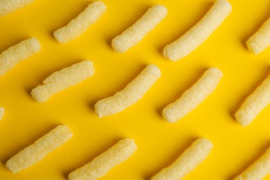 Photo of Tasty corn sticks on yellow background, flat lay