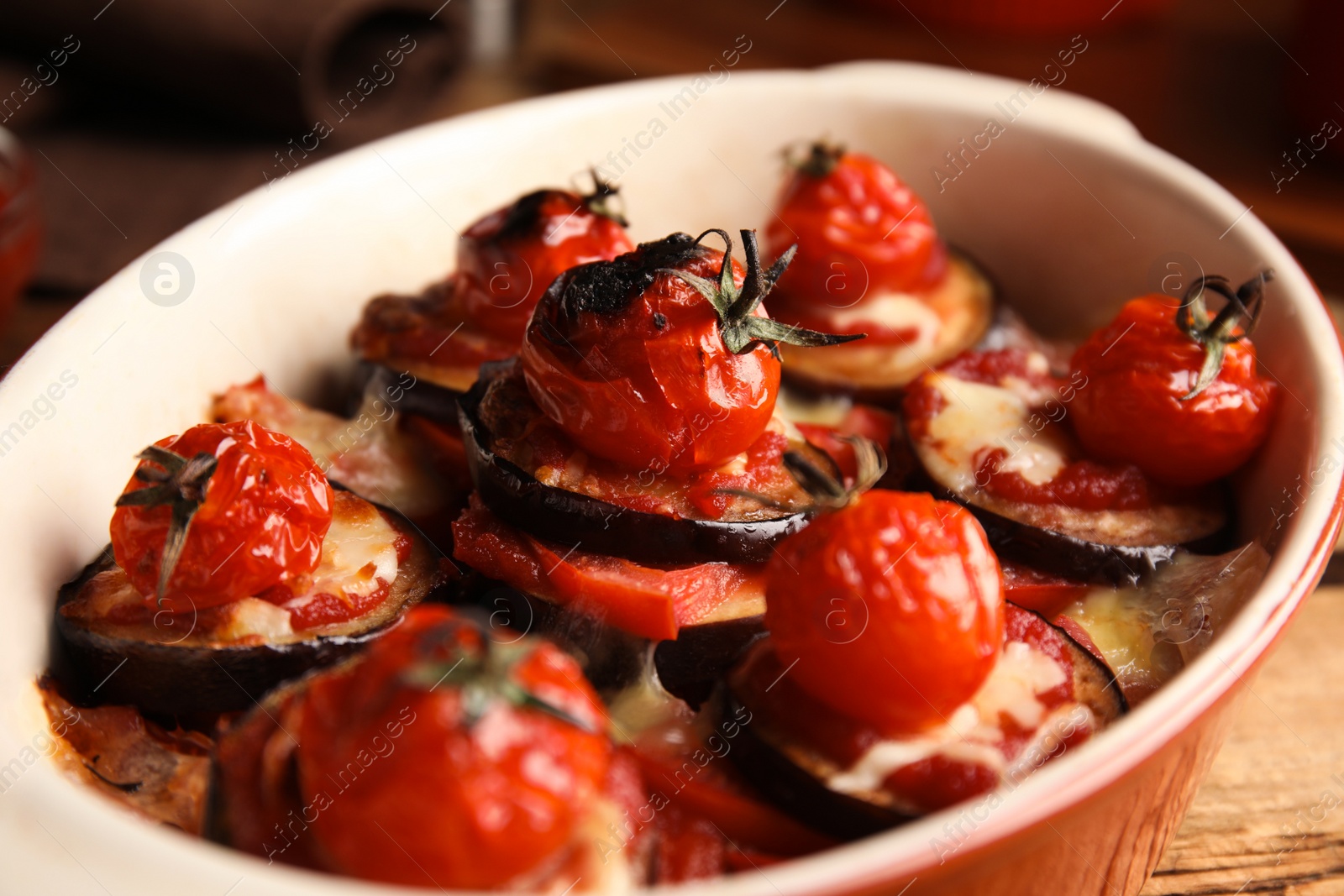 Photo of Baked eggplant with tomatoes and cheese in dishware on table, closeup