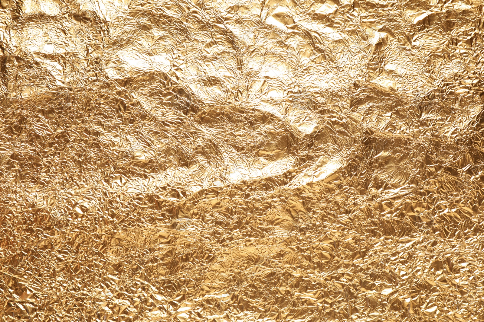 Photo of Crumpled gold foil as background, top view