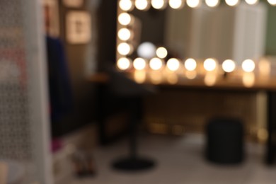 Blurred view of makeup room with stylish mirror near dressing table