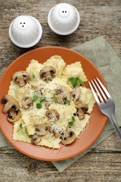 Photo of Delicious ravioli with mushrooms and cheese served on wooden table, flat lay