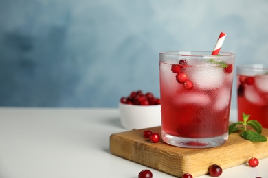 Photo of Tasty refreshing cranberry cocktail with mint on white table. Space for text