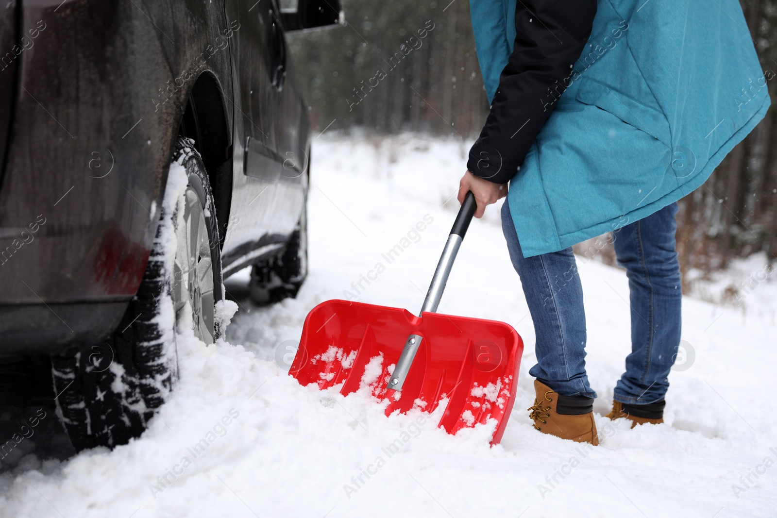 Photo of Man cleaning snow with shovel near stuck car outdoors