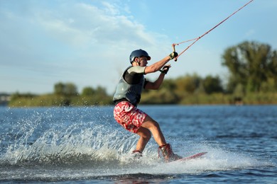 Photo of Teenage boy wakeboarding on river. Extreme water sport