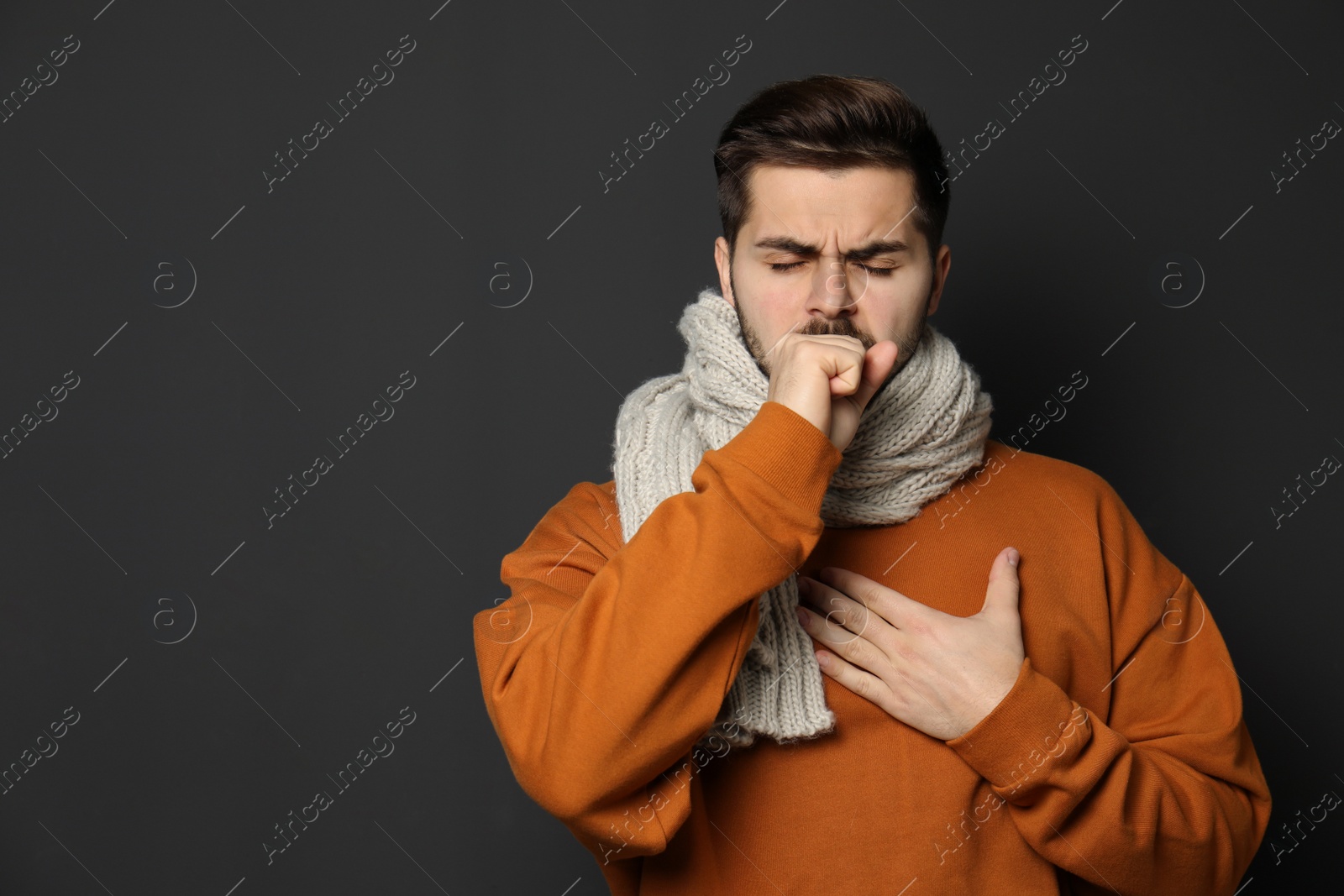 Photo of Handsome young man coughing against dark background. Space for text