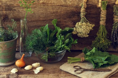 Photo of Different herbs, rusty scissors and burlap fabric on wooden table