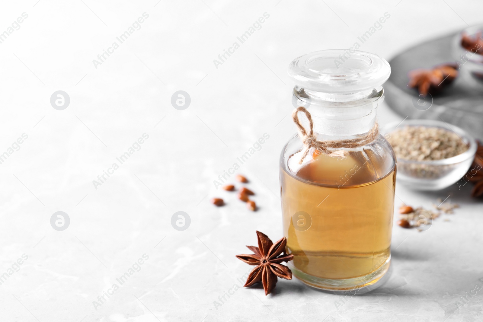 Photo of Anise essential oil and spice on light table, space for text