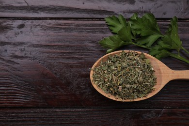 Photo of Spoon of dried aromatic parsley and fresh leaves on wooden table, flat lay. Space for text