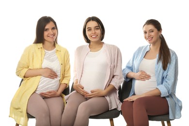 Happy pregnant women sitting on chairs against white background