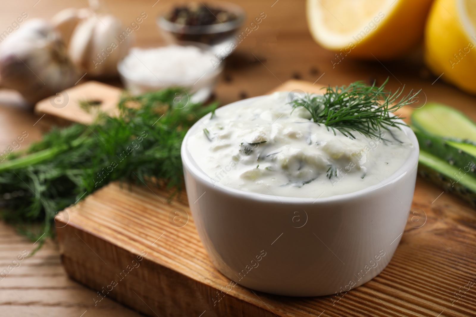 Photo of Cucumber sauce with ingredients on wooden background, space for text. Traditional Tzatziki