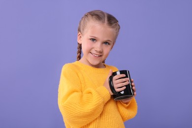 Photo of Happy girl with black ceramic mug on violet background