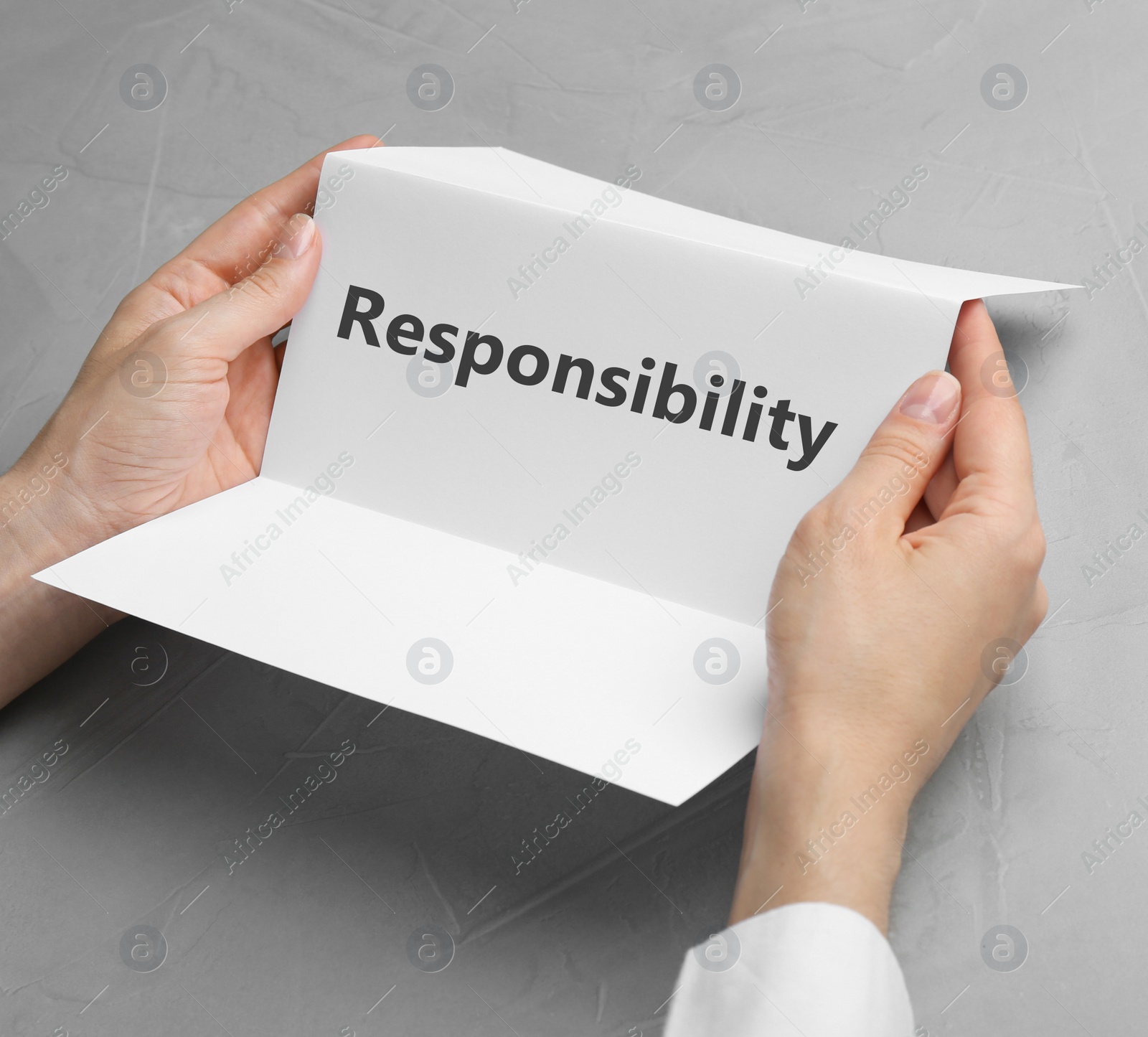 Image of Woman holding brochure with at grey table, closeup